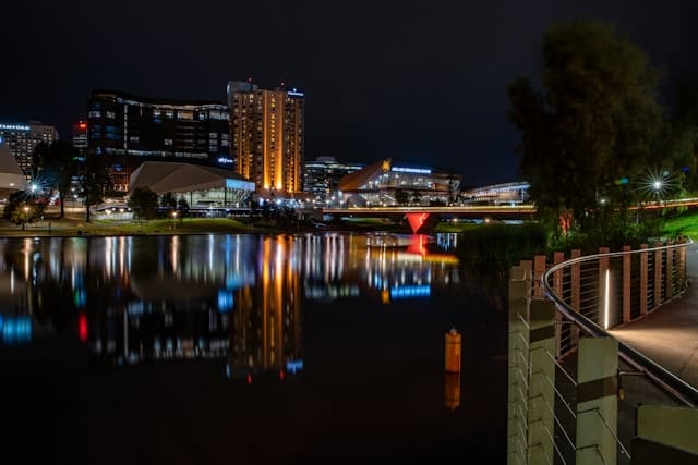 VIP Elite Escort Adelaide 13 a night scene of a city with a river and a bridge